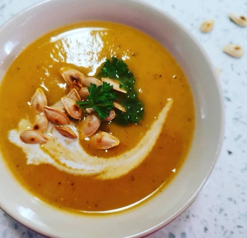 butternut soup topped with a dash of cream, toasted pumpkin seeds and fresh coriander